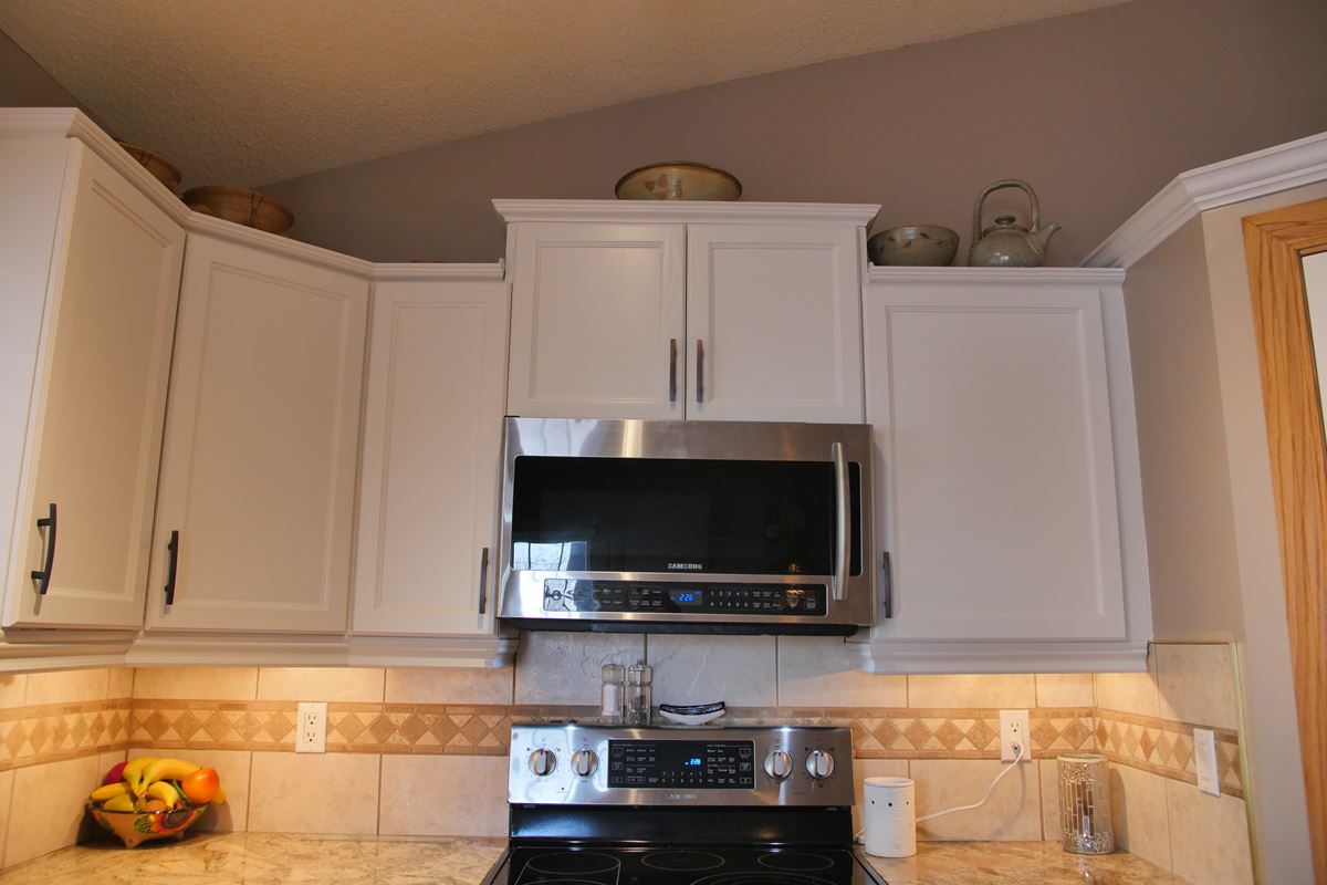 White painted upper kitchen cabinetry with brushed handles